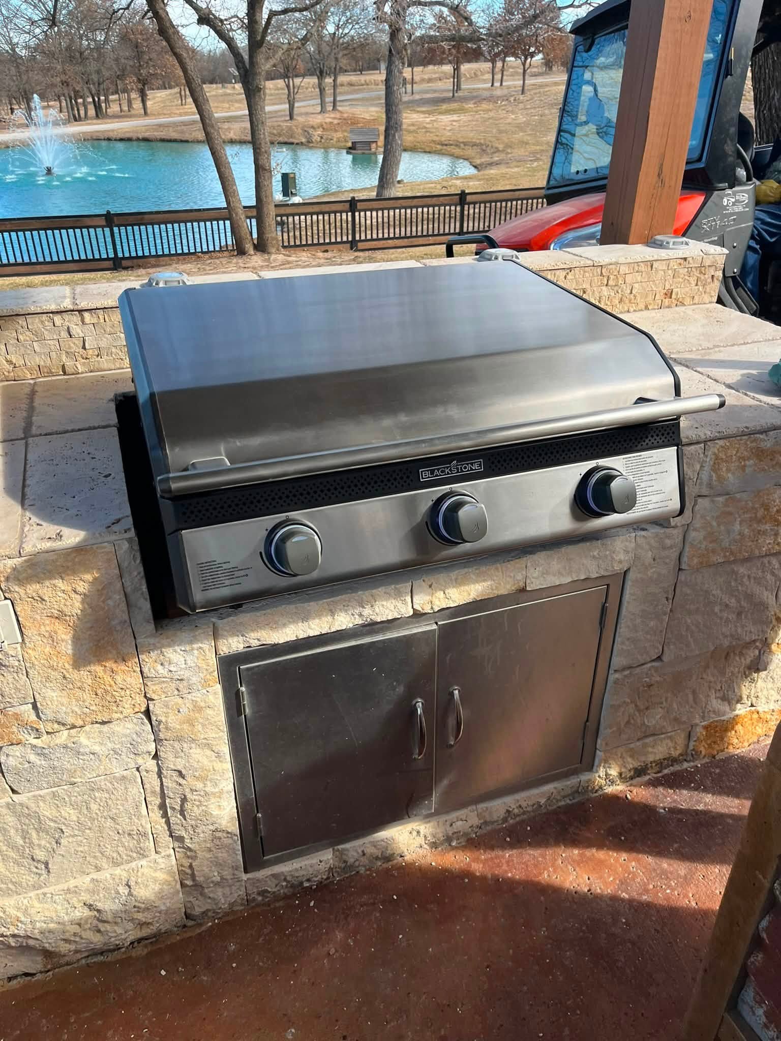 Built-in gas grill installed in a stone outdoor kitchen island